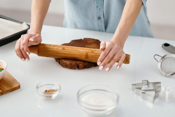 person flattening a chocolate dough with rolling pin